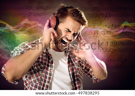 Young man listening to music in headphones. Colorful design on musical notes background.