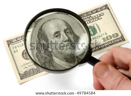 Hundred dollar bill under a magnifying glass is being inspected Conceptual photo isolated on white background