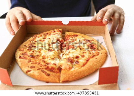 pizza in cardboard box with kids hands close up photo