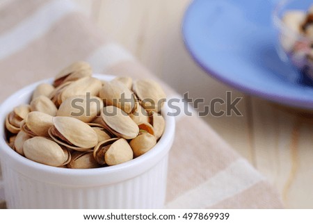 Close up of pistachio nut in cup on wooden background. Selective focus, decorated and blank space concept.