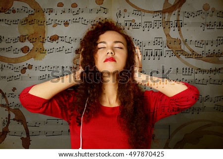 Young woman listening to music in headphones. Coffee stains on musical notes background.