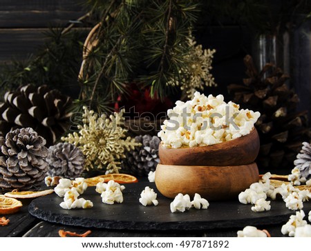 popcorn in a wooden plate on the background of Christmas trees and Christmas decorations, New Year offer, selective focus