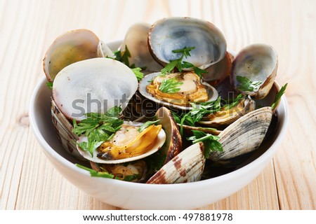 Clams steamed in white bowl on wooden table Royalty-Free Stock Photo #497881978