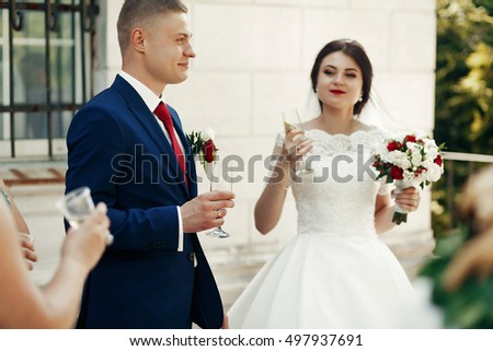Romantic bride & groom drinking champagne outdoors, wedding celebration