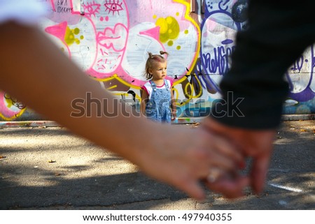 Blurred picture of mom and dad holding their hands together while little girl stands on the background