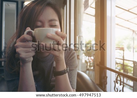 Closeup image of Asian woman drinking hot coffee with feeling happy in cafe , good lifestyle
