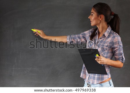 Young pretty female teacher writing on the chalkboard,copy space