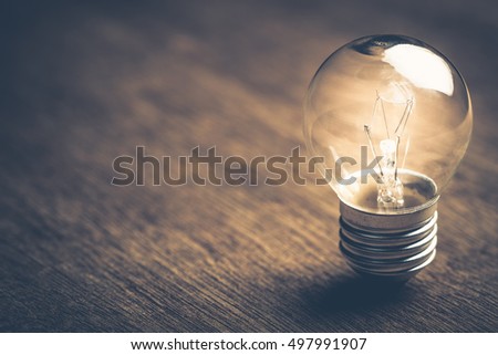 Small light bulb glowing on wood background