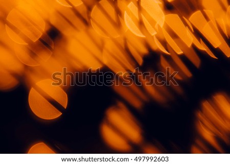 Bokeh dark orange circles and shade grasses on black background. Abstract  festive background.