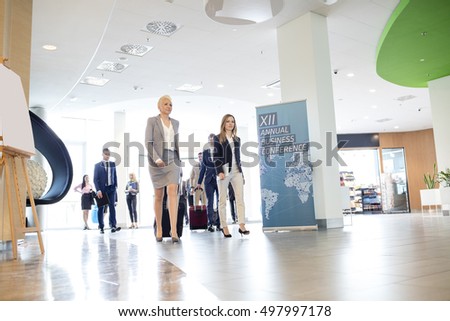 Business people with luggage walking in convention center