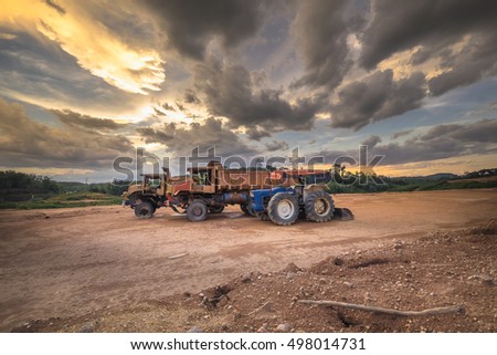 old truck and havy michine in construction side with dramatic cloudy during sunset hour