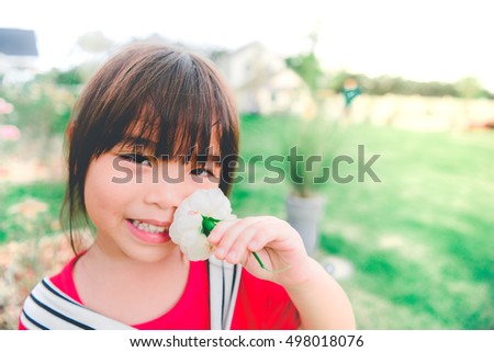 Closeup Little girl has a flower in hand bright tone,sunny day,bright sunlight