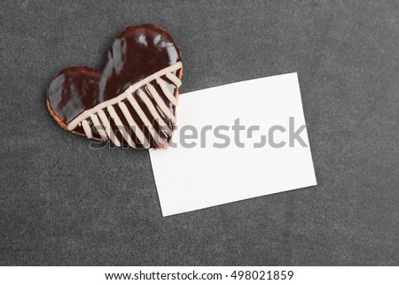 Sweet sugar cookies on a black surface. Sponge cake in heart shape with a striped pattern. A blank greeting card. With place for text.