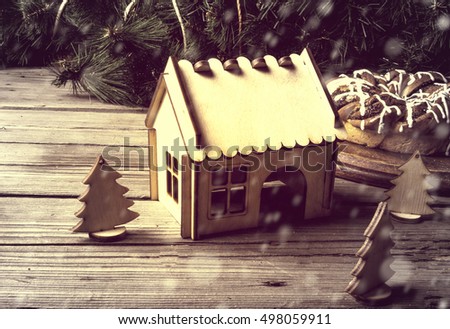Traditional Christmas decorations and toys. Wooden house and Christmas trees next to a sweet homemade cake on the background of pine branches. Toned, Copy space