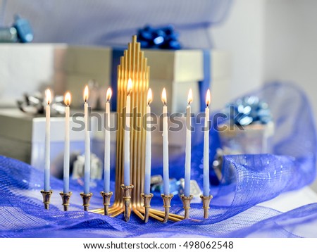 Beautiful Chanukah decorations in blue and silver with gifts and dreidels and a Chanukiah with nine Chanukah candles for the Jewish holiday Hanukkah with copy space.