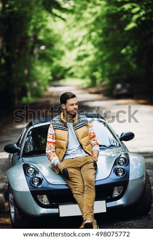 man sitting on the hood of his car on the road