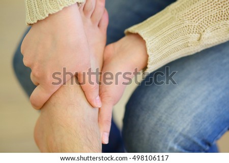 Woman massages male leg, part of body, swelling right after sprained foot