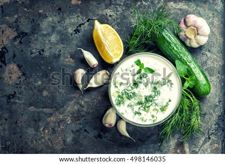 Tzatziki sauce with ingredients cucumber, garlic, dill, lemon, mint. Food background. Vintage style toned picture