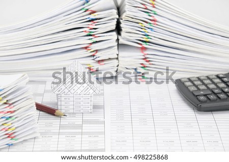 House and pencil on finance account have blur pile overload document of report and receipt with colorful paperclip and calculator as background. Business and finance concept rich and successful photo.