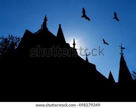 halloween background with silhouettes of castle roofs with  weather vanes and three flying bats