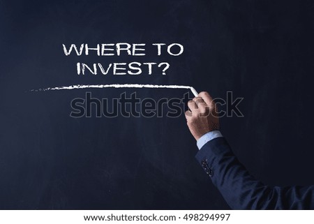 Businessman writing WHERE TO INVEST? on Blackboard