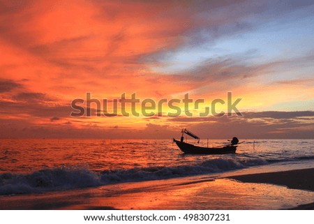 Beautiful sunrise on the beach and silhouette of fishing boat.