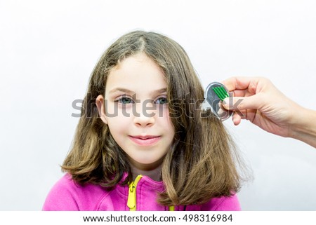 Lice treatment. Girl gets combed for lice with lice comb. Studio portrait. 