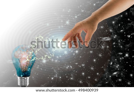 One hand that lights a bulb with planet earth in the starry sky
