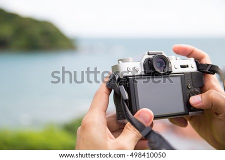 Hand holding a mirrorless digital camera prepare for take a landscape photo
