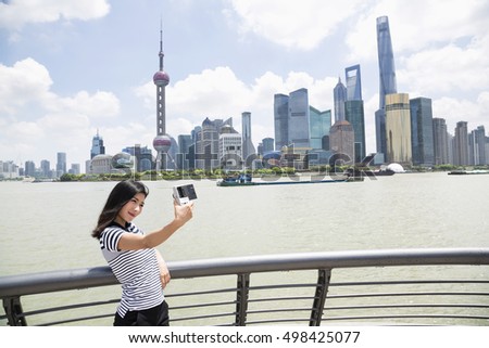 Young woman taking selfie while standing by railing against Pudong skyline