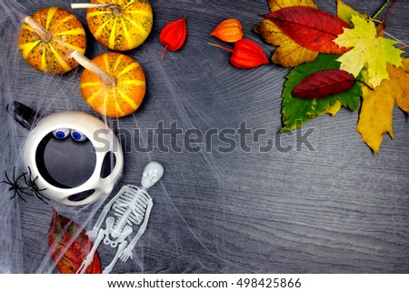 Elements of halloween decoration. Orange pumpkins, spiders, autumn leaves, skeleton, jack skelington cup with eyes in it and web isolated on wooden background