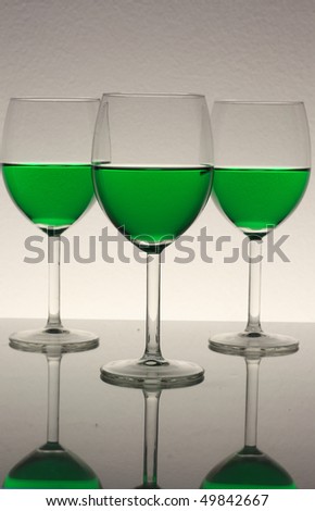 three wine glasses with green wine