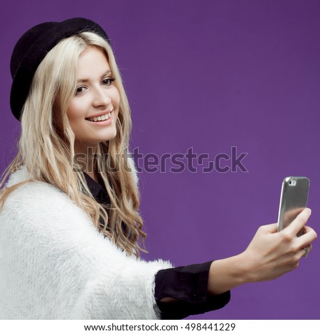 Fashion young girl taking picture of herself, selfie. Purple background