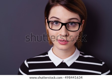 Close up on young woman in black eyeglasses and striped sweater with collar over dark background