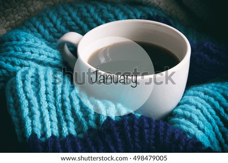 A cup of coffee, white cup in a scarf, the inscription on the picture