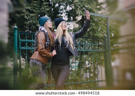 two beautiful girls are photographed on the street in hats and classy jackets