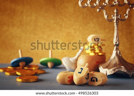 Image of jewish holiday Hanukkah with wooden dreidels colection (spinning top) and chocolate coins on the table. Selective focus