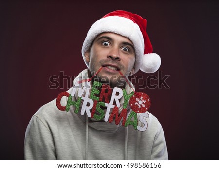 Young funny guy with Christmas hat on red velvet background