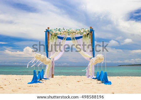 Wedding on the beach . Wedding arch decorated of blue material and white flowers on tropical sand beach. Wedding and honeymoon concept.