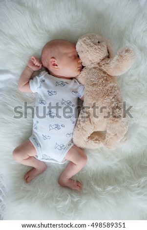 Baby sleeping on white fur with stuffed animal