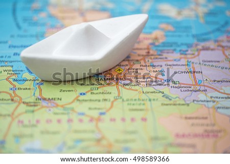 White toy boat near Hamburg on a geographical map background