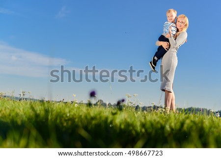 Mother walks with a child in the summer in the park against the blue sky. family values