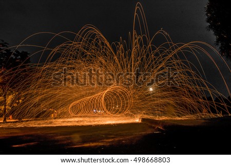 Showers of hot glowing sparks from spinning steel wool.
