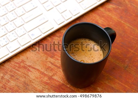 coffee cup and keyboard. Top view with wooden table.