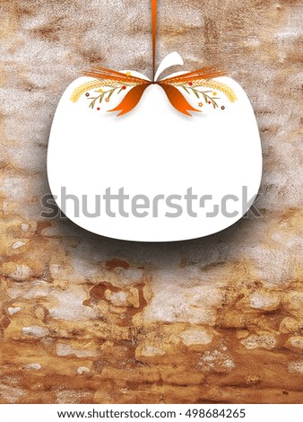 Close-up of one blank pumpkin shaped frame hanged by orange ribbon on brown weathered brick wall background