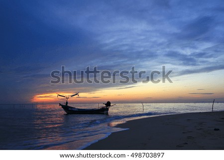 Beautiful sunrise on the beach and silhouette of fishing boat.