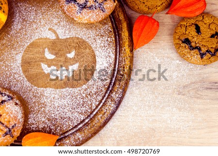Spooky cupcakes, pumpkin, leaves and silhouette of bat on wooden dishes