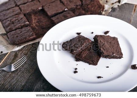 Cake chocolate brownies on white plate on vintage wooden background