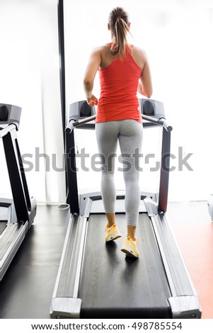 Beautiful young woman running on a treadmill infitness center