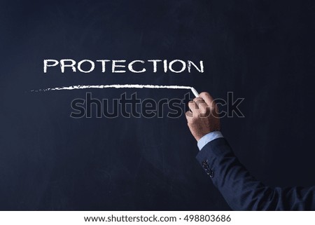 Businessman writing PROTECTION on Blackboard
